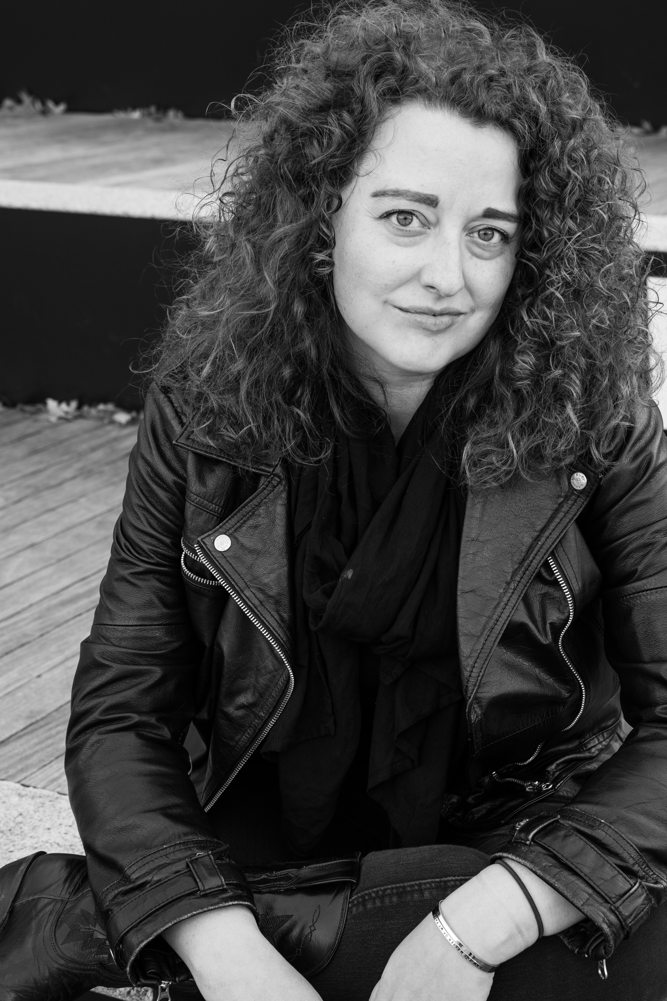 jeanna kadlec sitting in front of the brooklyn museum in a leather jacket and cowboy boots; the steps have text that say "demand the space your dignity deserves"